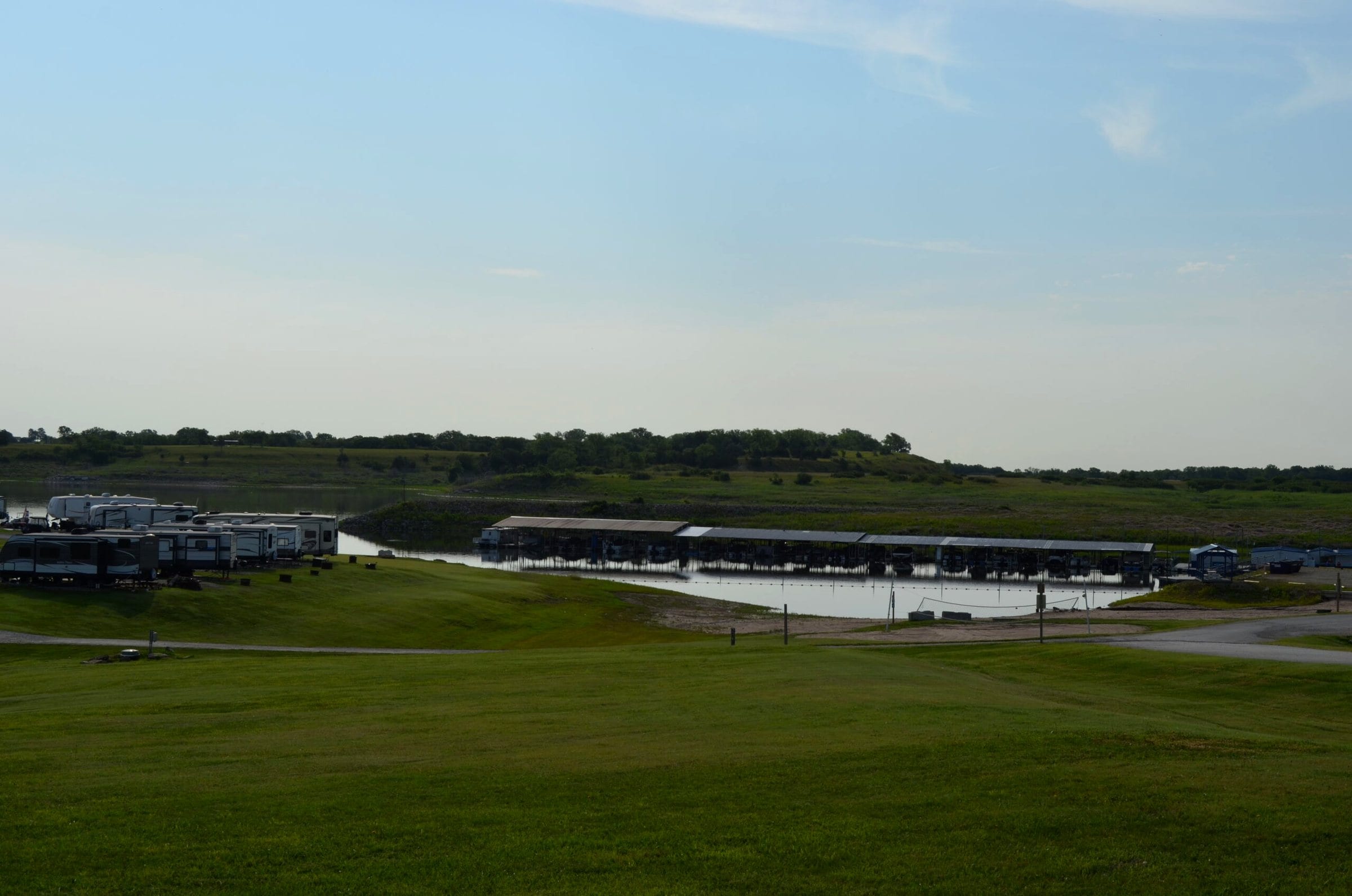 Calm cove with covered boat slips along the far shore and campers on the hill