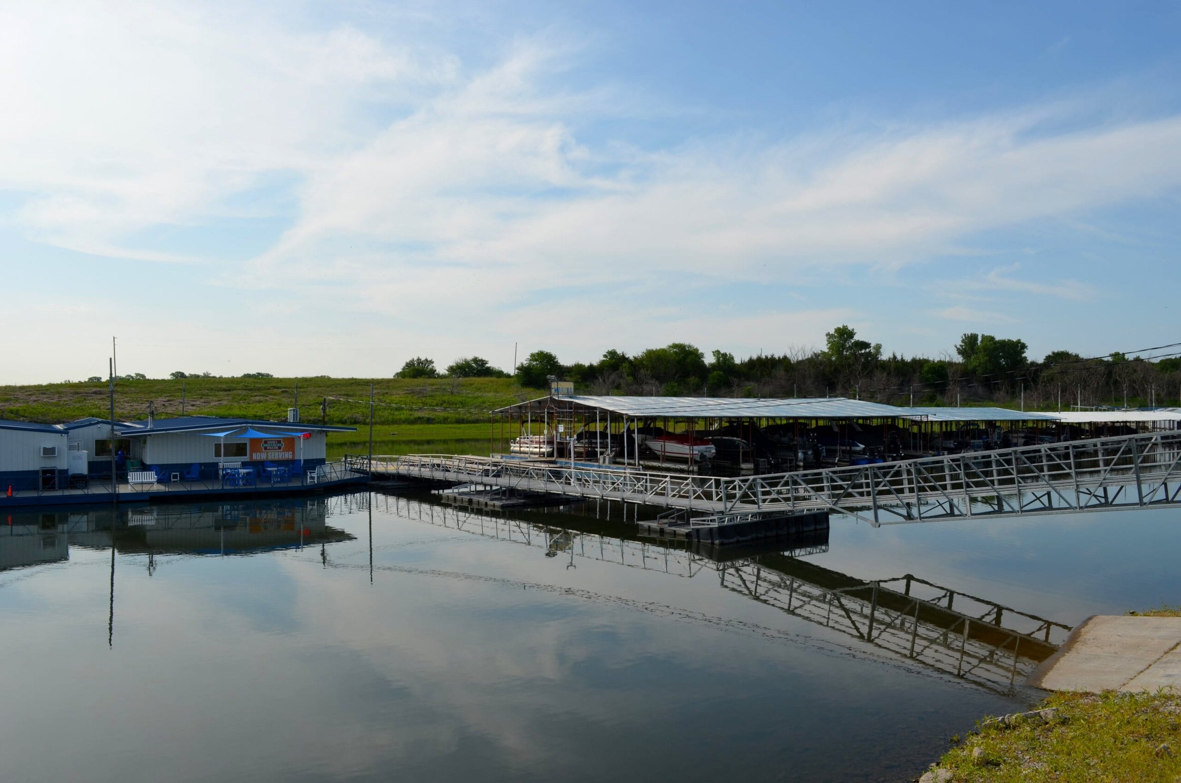 Covered slip dock reaching out over still water toward the marina