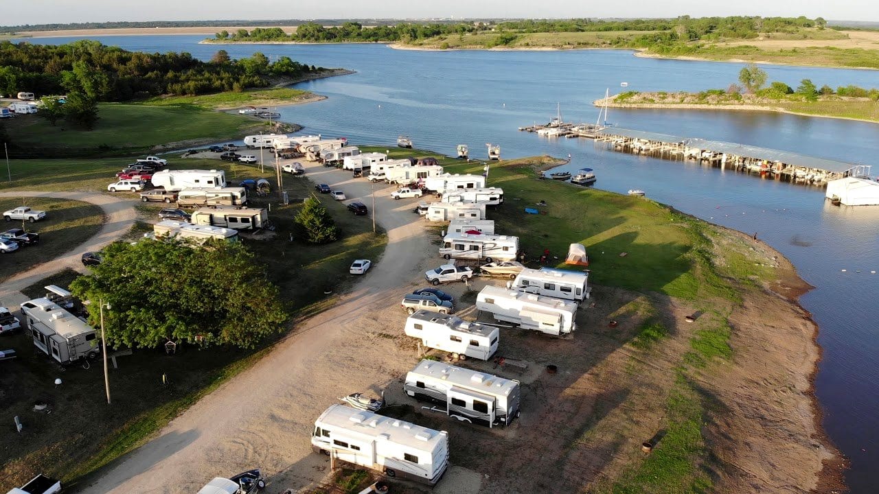 Aerial view of RVs lined up along the shoreline, with the docks reaching out into Milford Lake